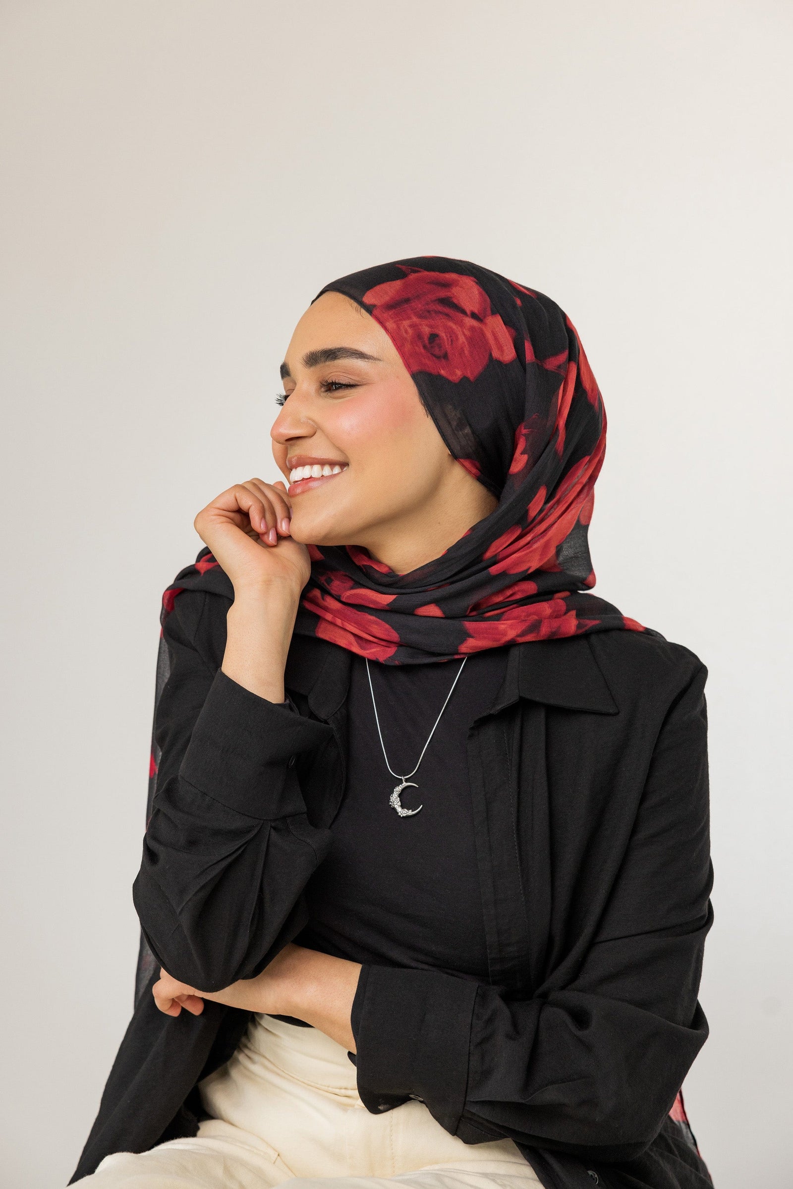 A model wearing the Damask Rose Crescent Necklace at its full 22-inch length. The necklace rests gracefully on the collarbone, highlighting the crescent moon pendant with rose detailing against a simple, neutral-toned outfit.