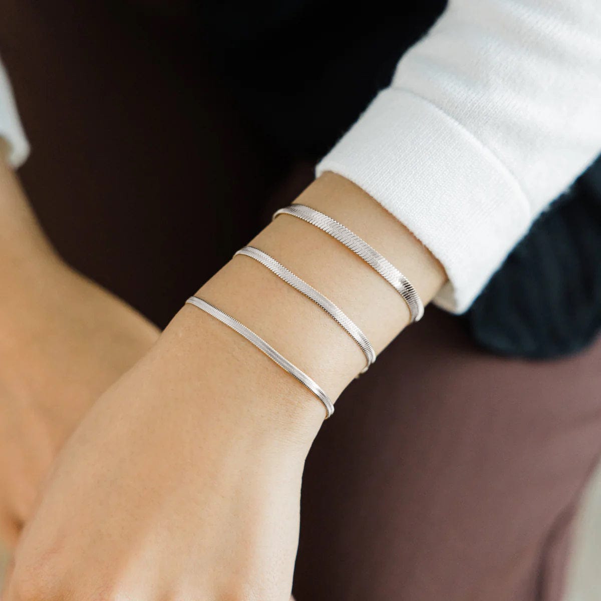 Photo of the model wearing three silver bracelets in different thickness.
