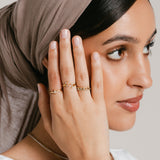 Model wearing an 18k gold-plated ring stack featuring a Triple Marquise Bezel Ring on the index finger, an Olive Branch Marquise Bezel Ring on the middle finger, and a Five-Stone Bezel Ring stacked above a Bezel Band on the ring finger.