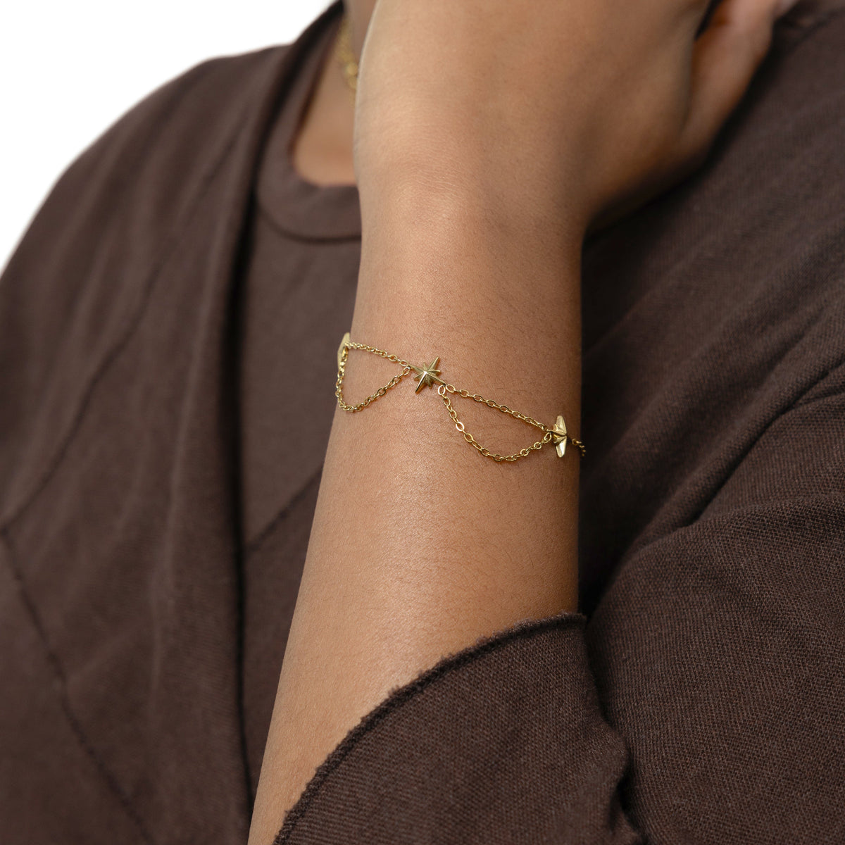 Picture of the gold North Star Bracelet worn by the model on their left hand.