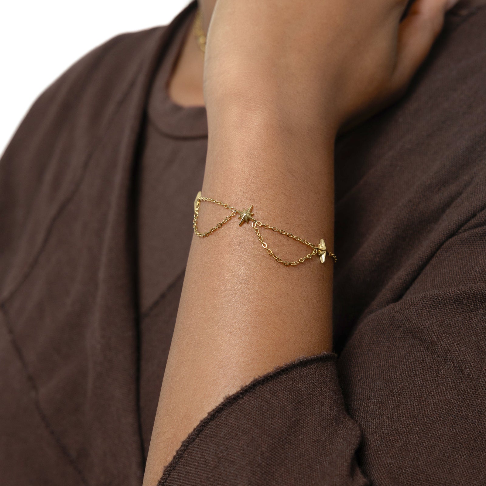 Picture of the gold North Star Bracelet worn by the model on their left hand.