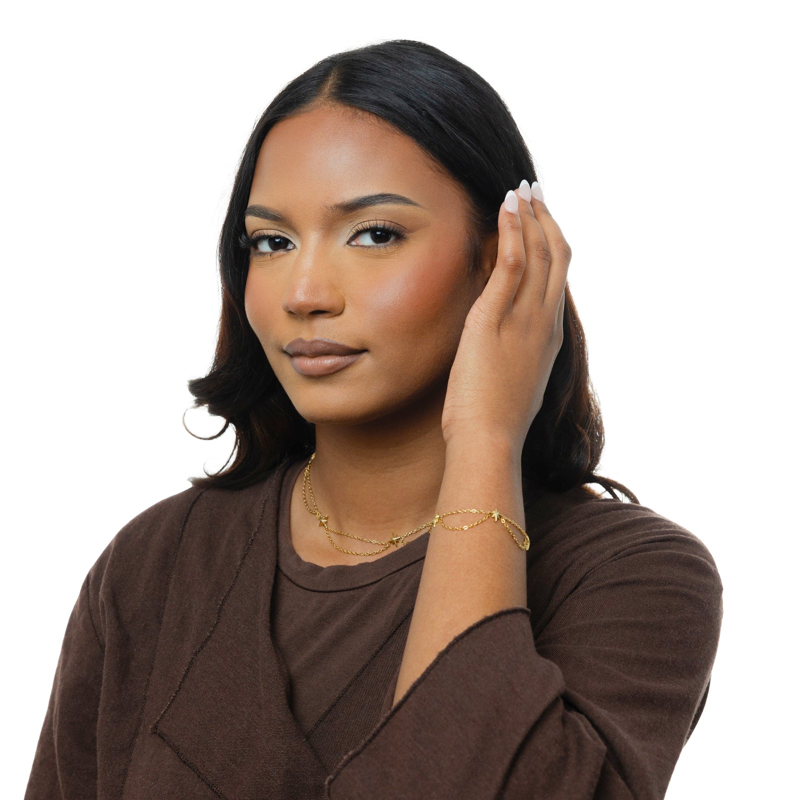 Photo of the model tucking their hair behind their left ear, the model is wearing the gold North Start bracelet on their left hand.
