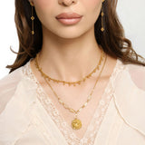 Woman wearing an 18k gold plated layered necklace with a chrysanthemum flower pendant and pale yellow tube beads
