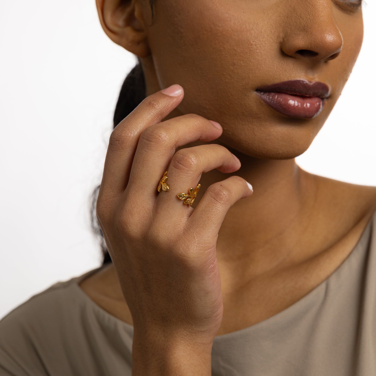 Woman wearing the gold Olive Branch Ring, hand raised near face