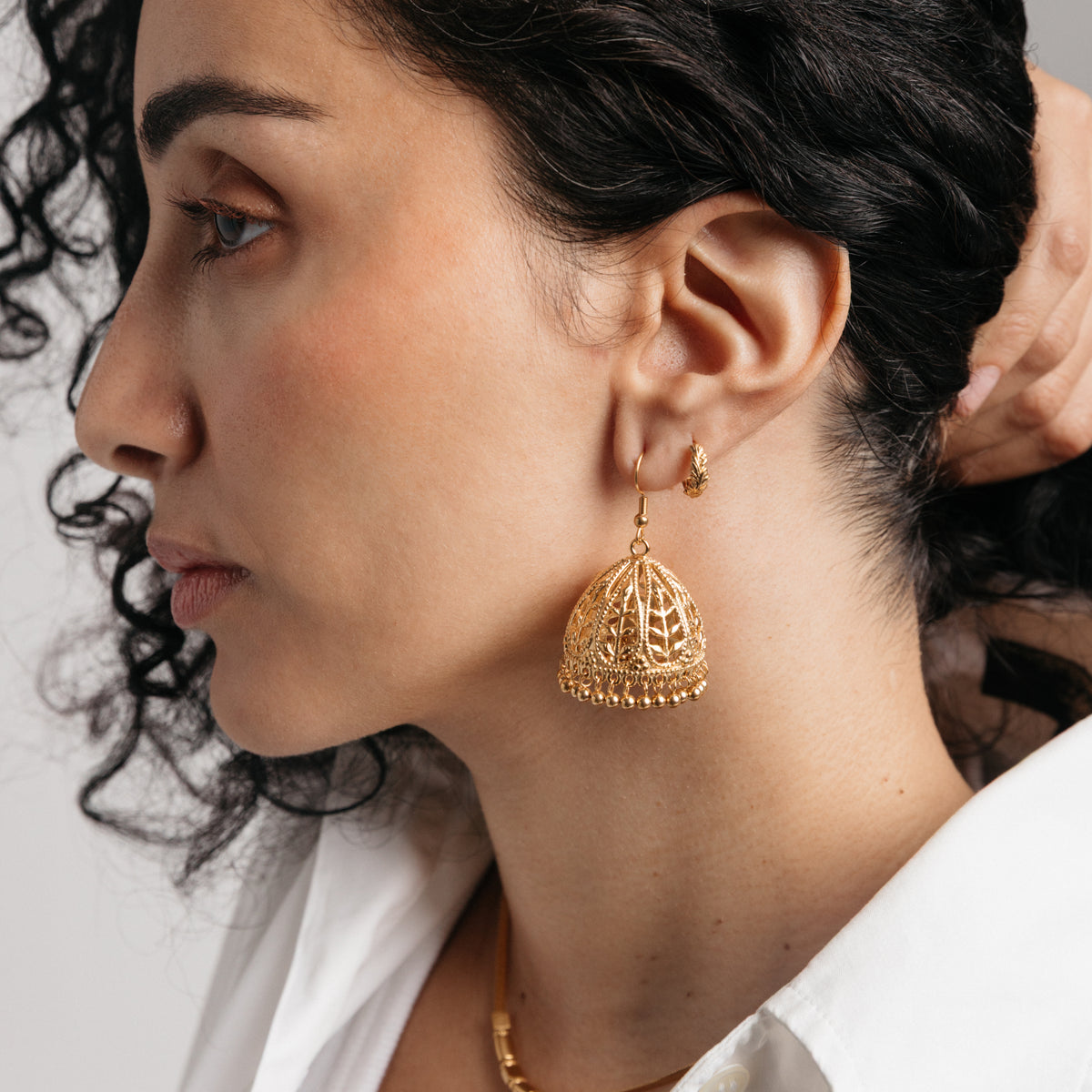 Model styled in 18k gold-plated Nominal jewelry featuring an ear stack with the Olive Branch Jhumka Earrings and Palestinian Olive Huggie Hoops.