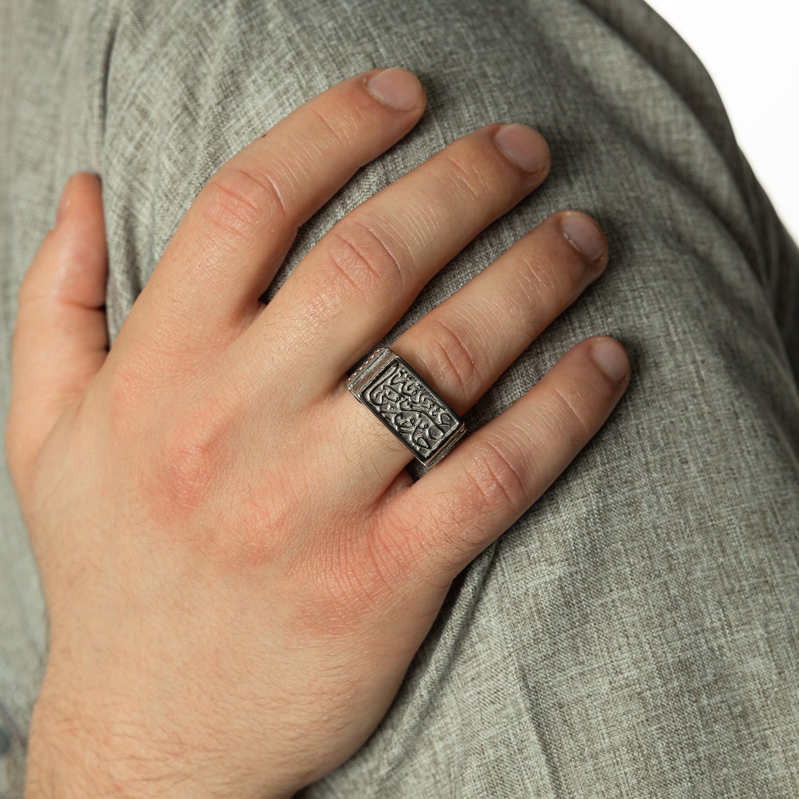 Photo of the model's right hand on a gray fabric. Model wearing the Our Roots Run Deep Ring | Men on their right ring finger.