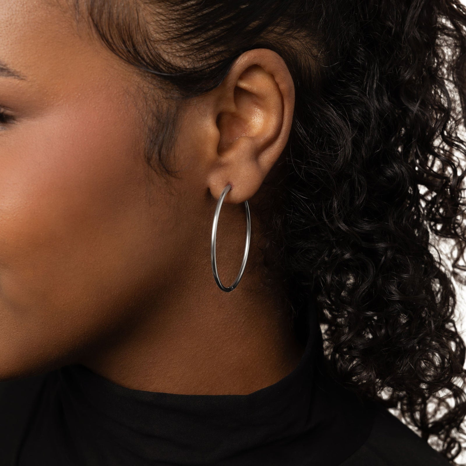 Close up of the silver Oversized Essential Hoops | 40mm as worn by the model on their left ear.
