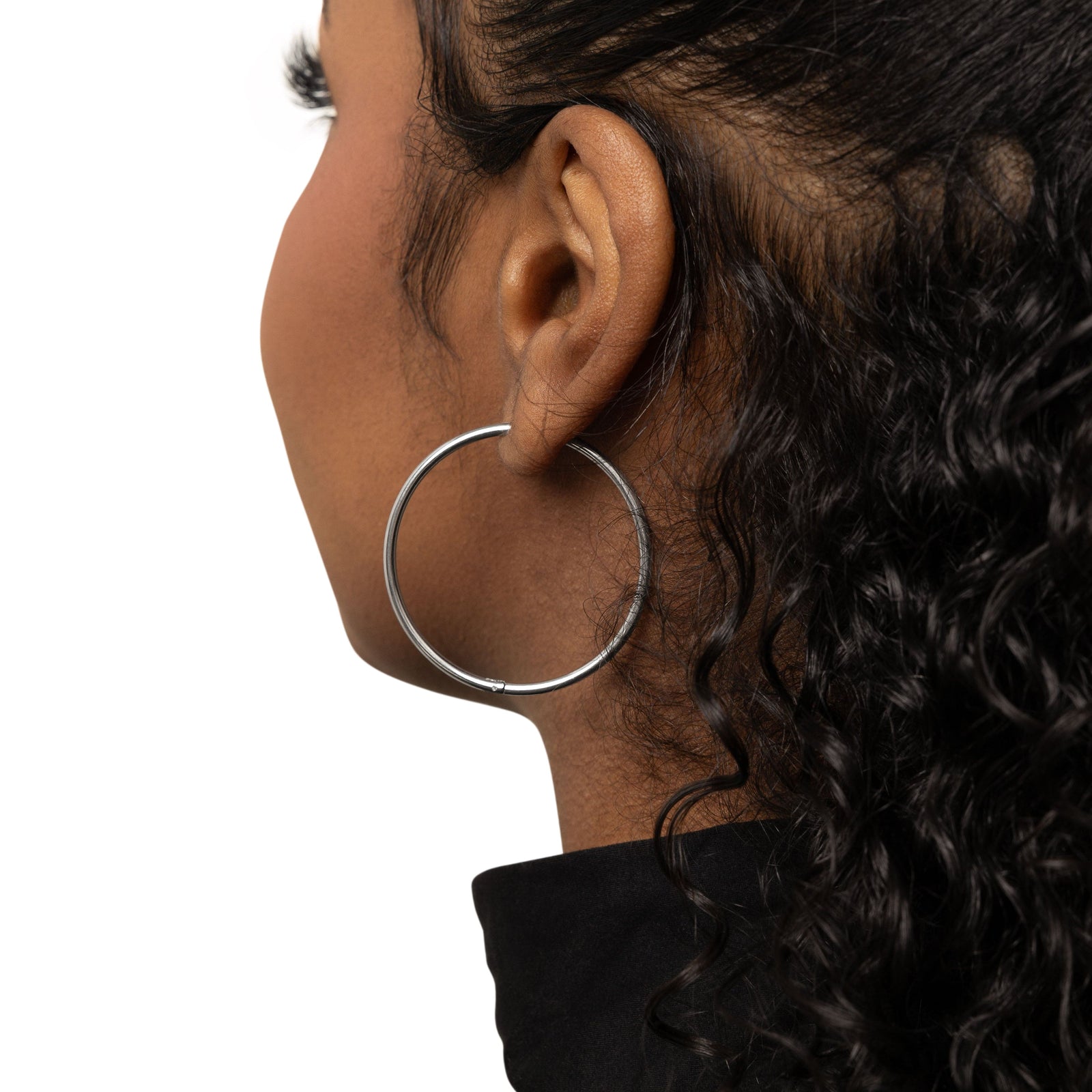 Close up of the silver Oversized Essential Hoops | 40mm on the model's left ear.