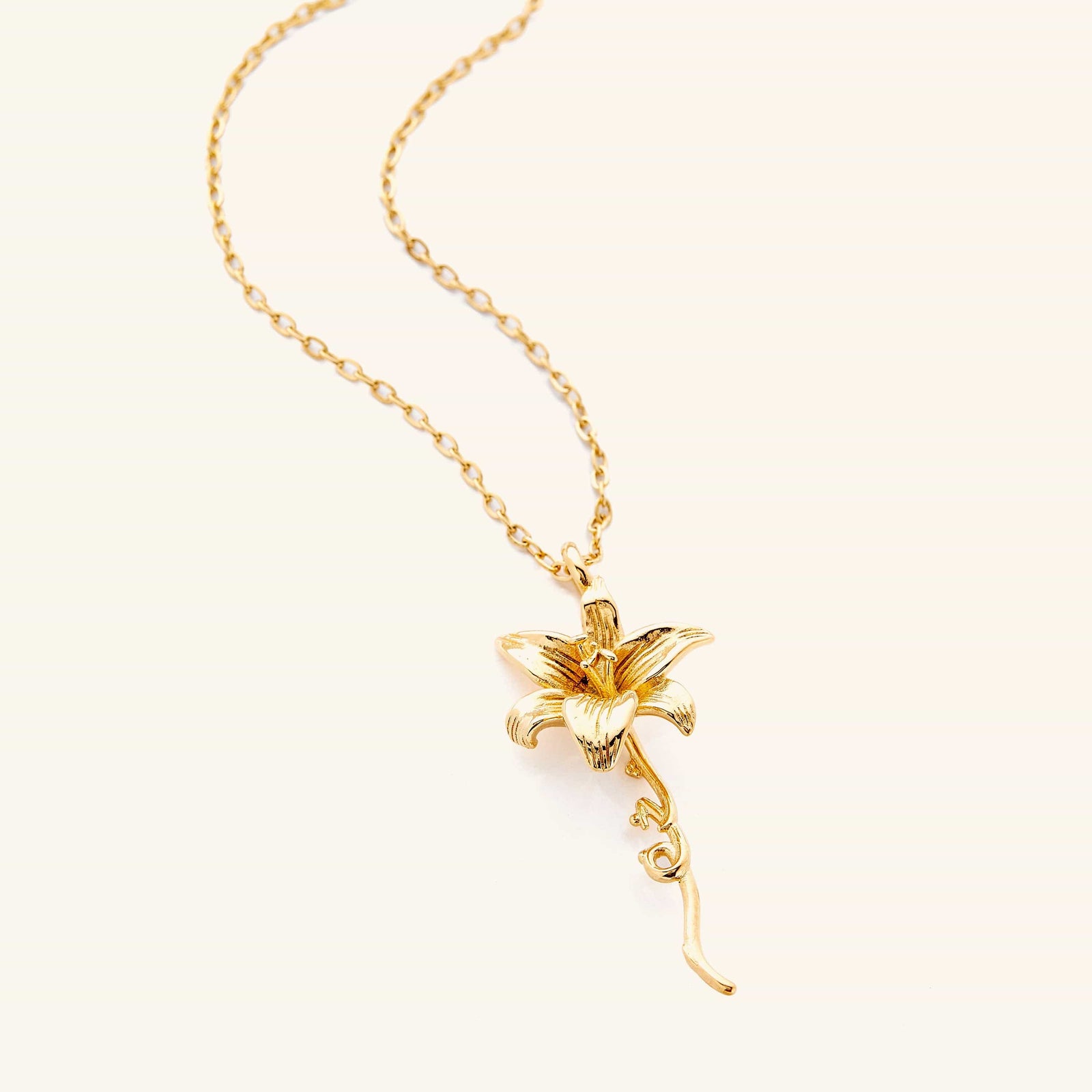 Photo of an 18k gold plated necklace that features the Lily that is a flower that represents a fresh start, and with that, we’ve paired it with the Arabic word for ‘passion’, curving in calligraphy out of the stem of the flower