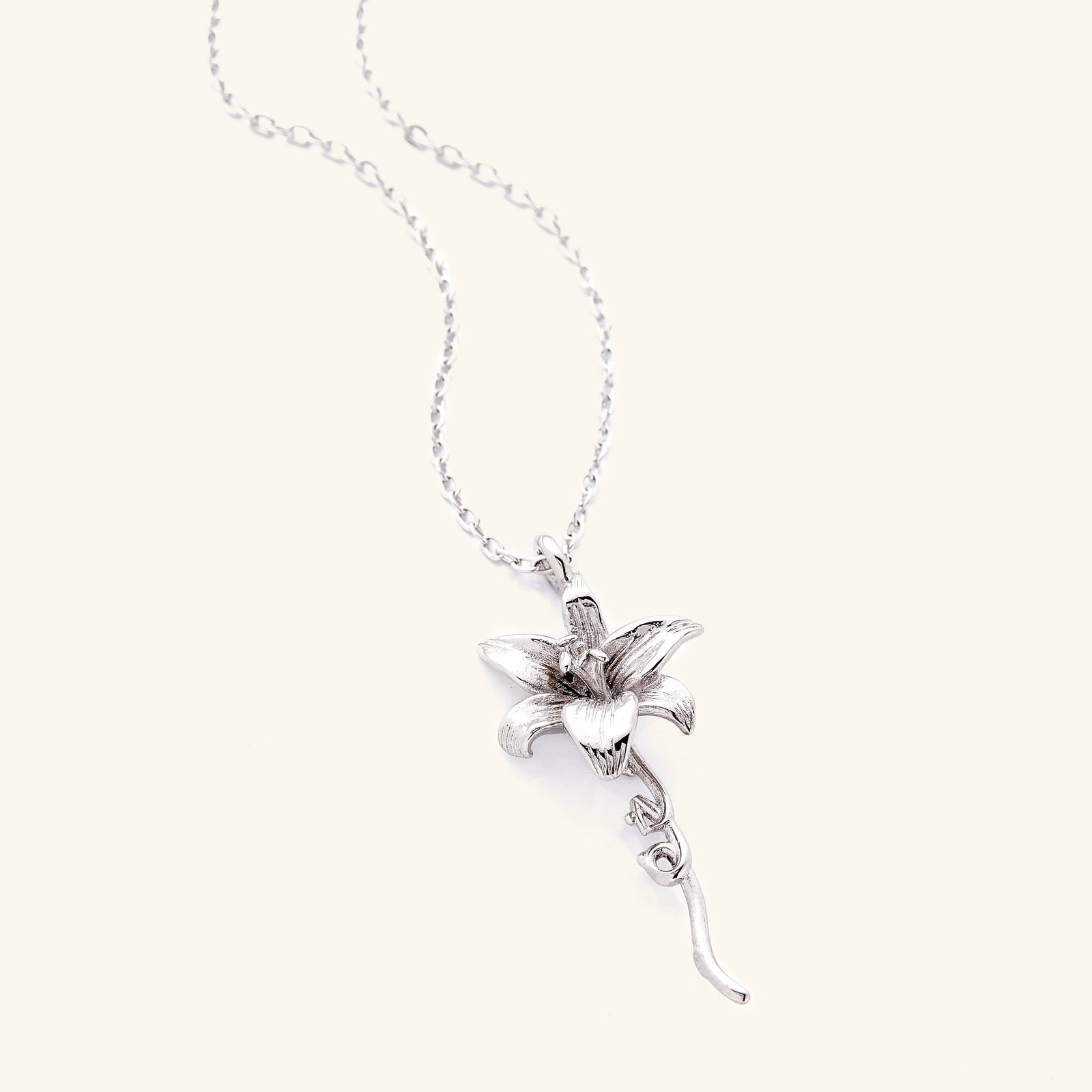 Photo of silver necklace that features the Lily that is a flower that represents a fresh start, and with that, we’ve paired it with the Arabic word for ‘passion’, curving in calligraphy out of the stem of the flower