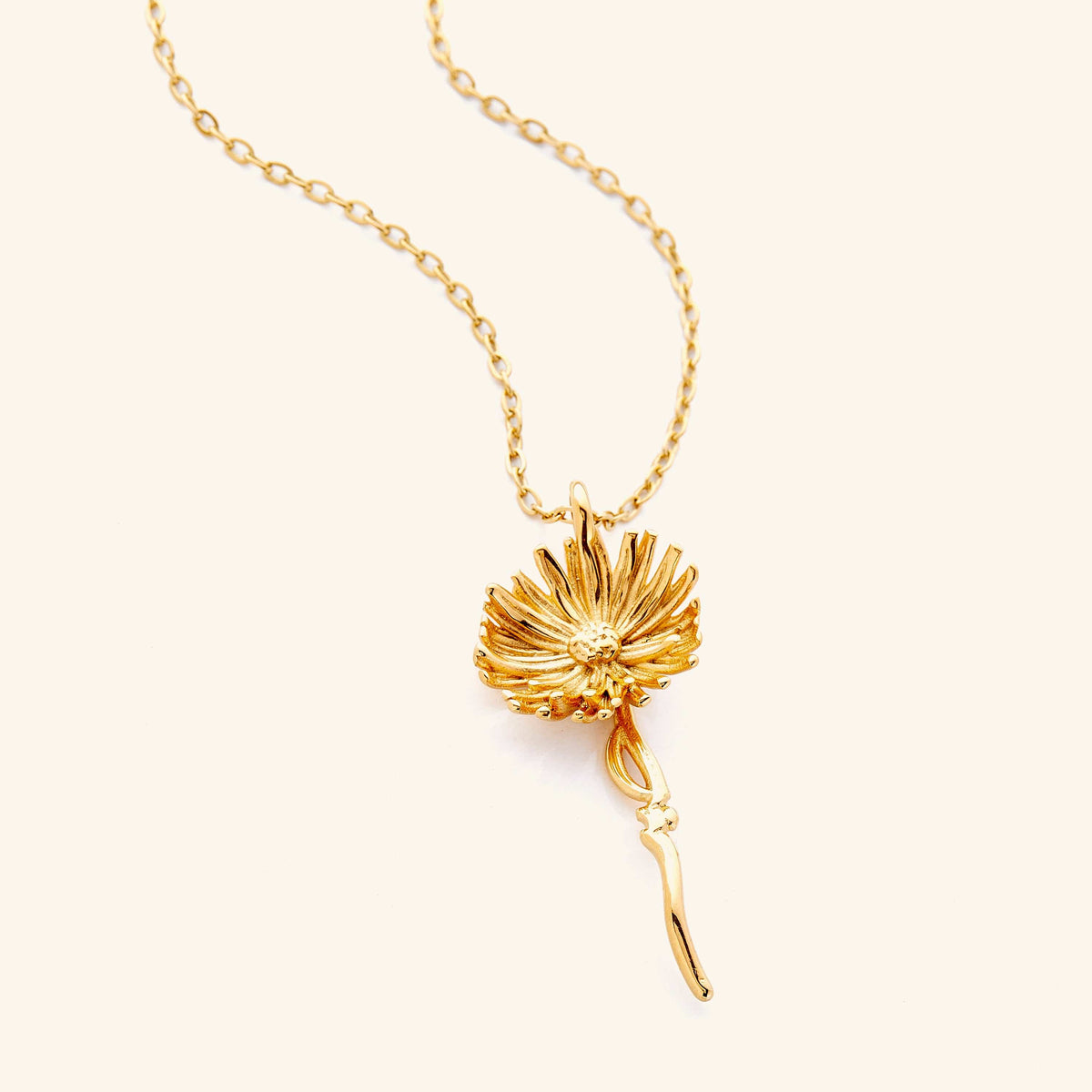 An 18k gold plated necklace with the aster flower shaped pendant that features  Arabic word for ‘patience’, curving in calligraphy out of the stem of the flower.