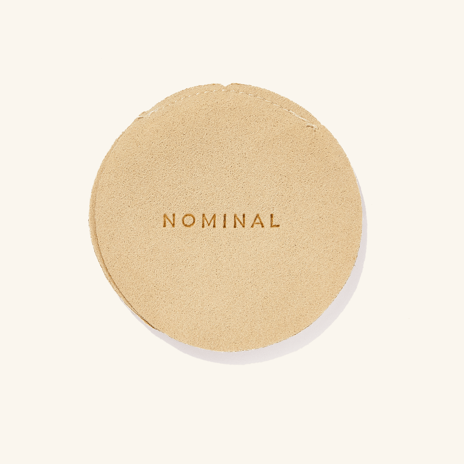 The Watermelon Hoops presented in a Nominal branded beige velvet drawstring pouch, highlighting the elegant and protective packaging accompanying the jewelry piece.