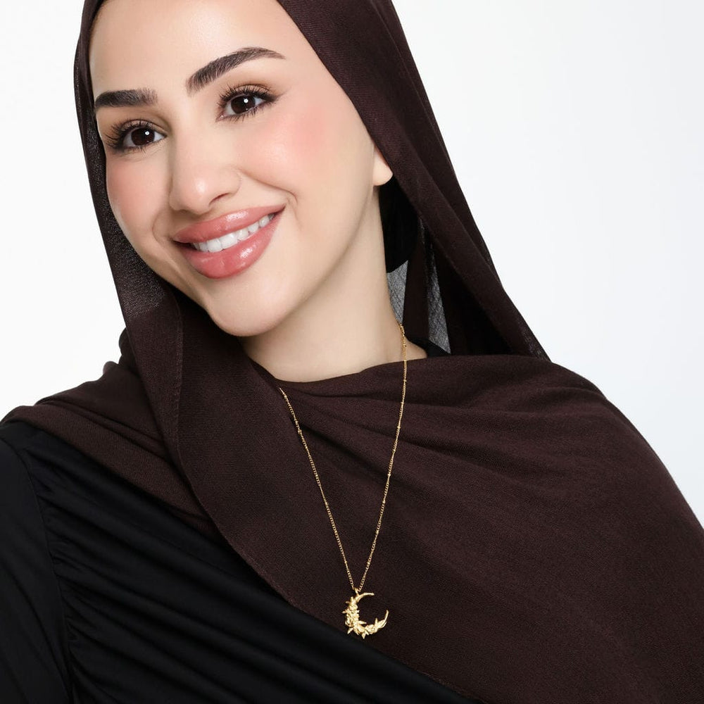 Photo of the model smiling, the model is wearing the gold Palestine Poppy Crescent Necklace.