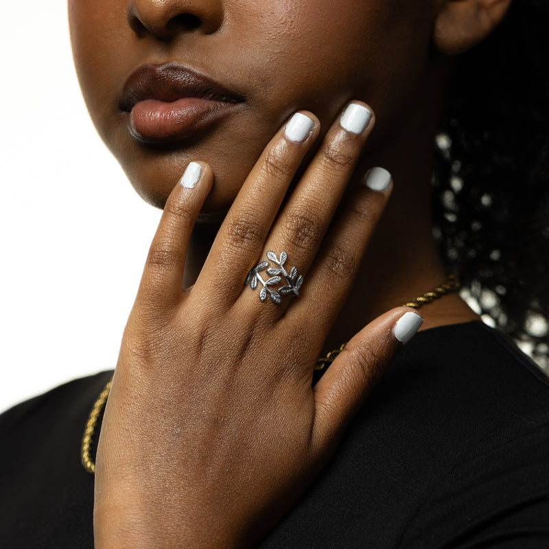 Woman pimage_ her hand near her face pimage_ styled with a silver palestine olive leaf ring and black top.