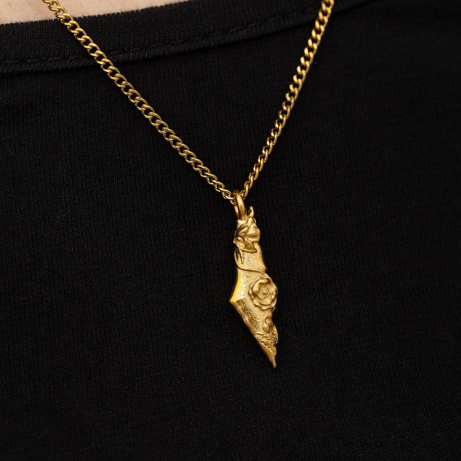 Close up of the gold pendant on a black background.