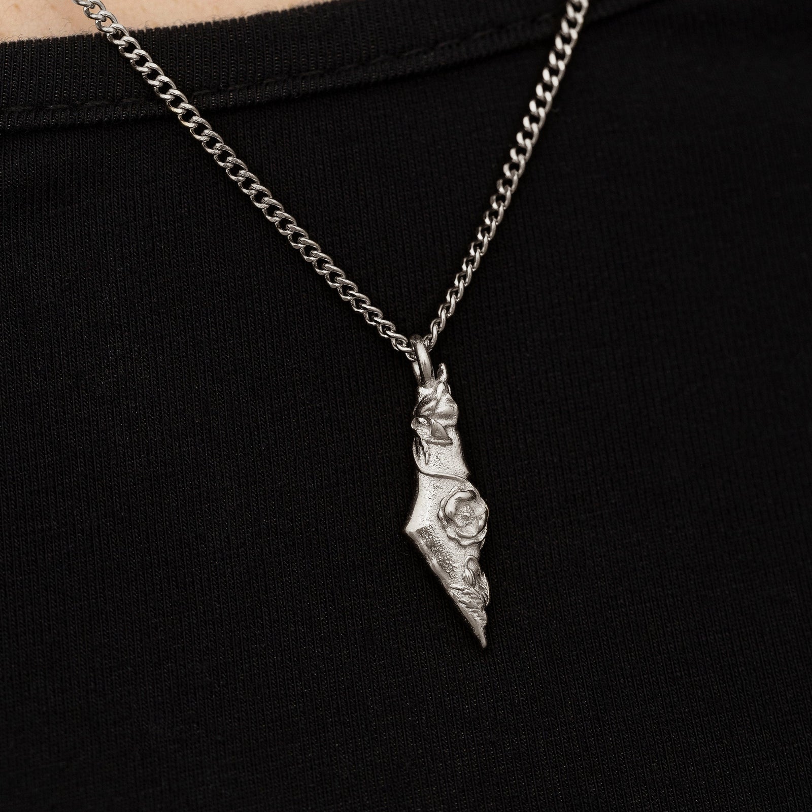Close up of the silver pendant on a black background.
