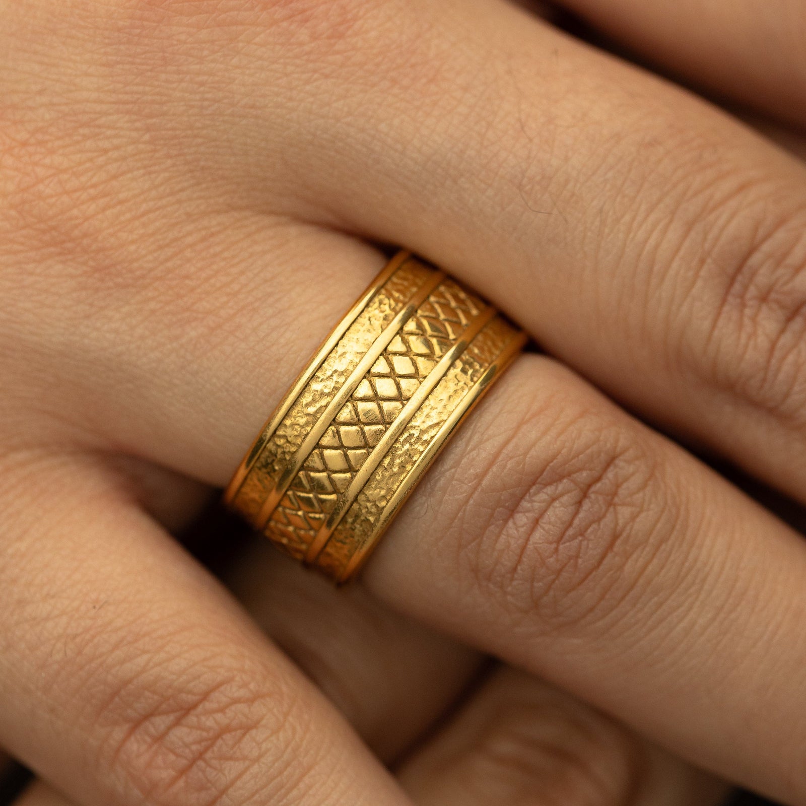 Woman wearing the gold Palestine Tribute Ring with textured edges and a diamond-patterned center on her finger in a close-up shot.