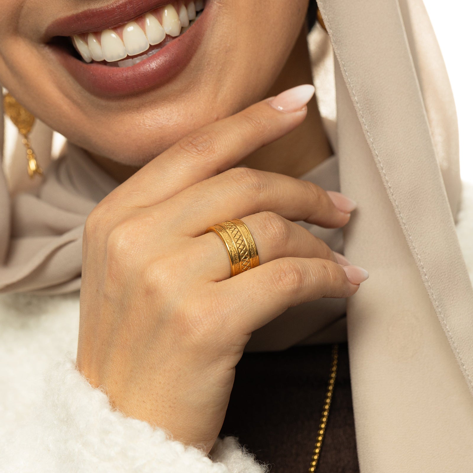 Woman wearing the gold Palestine Tribute Ring with textured edges and a diamond-patterned center on her finger in a close-up shot.