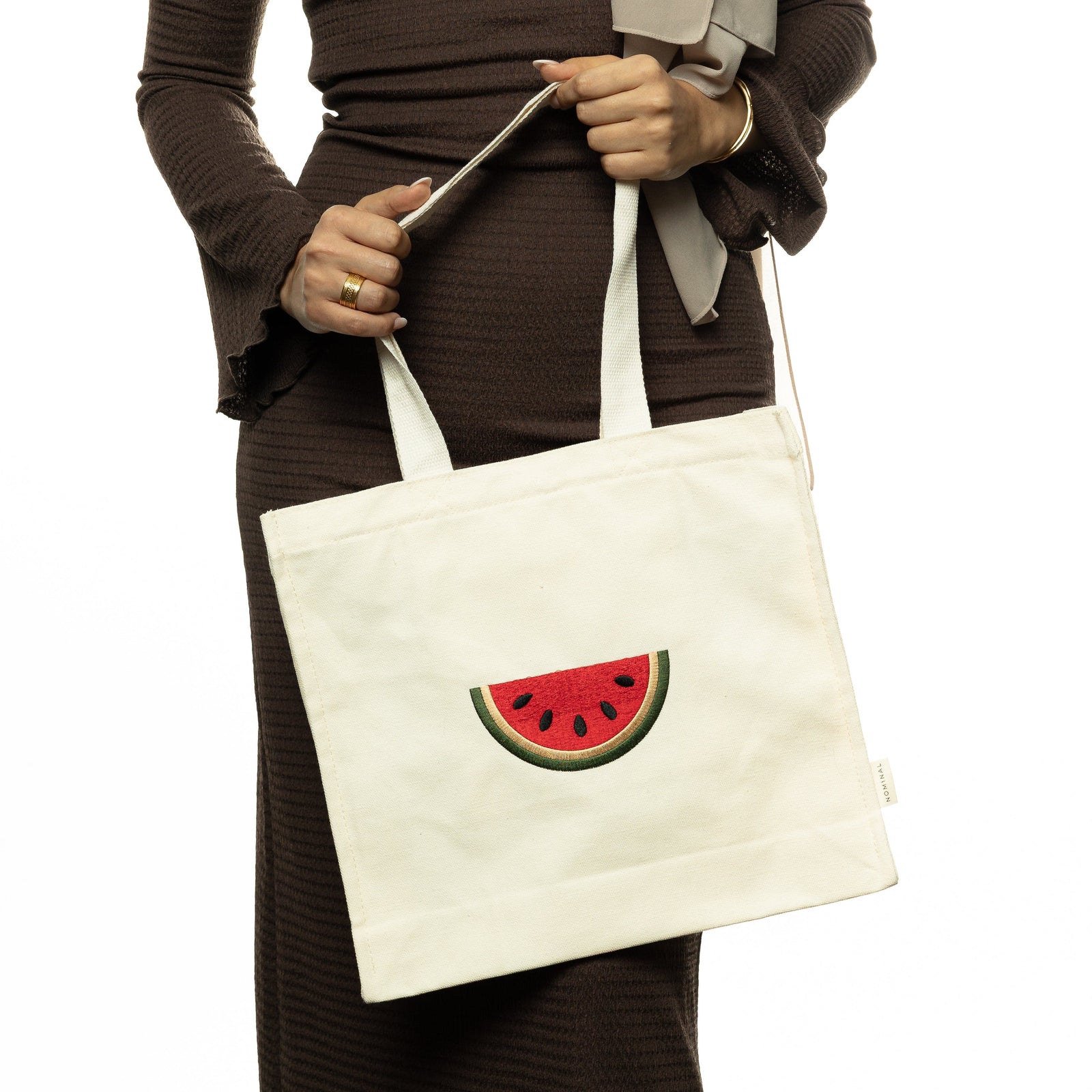 Photo of the model holding the Palestine Watermelon Tote by its strap showing the tote's design.