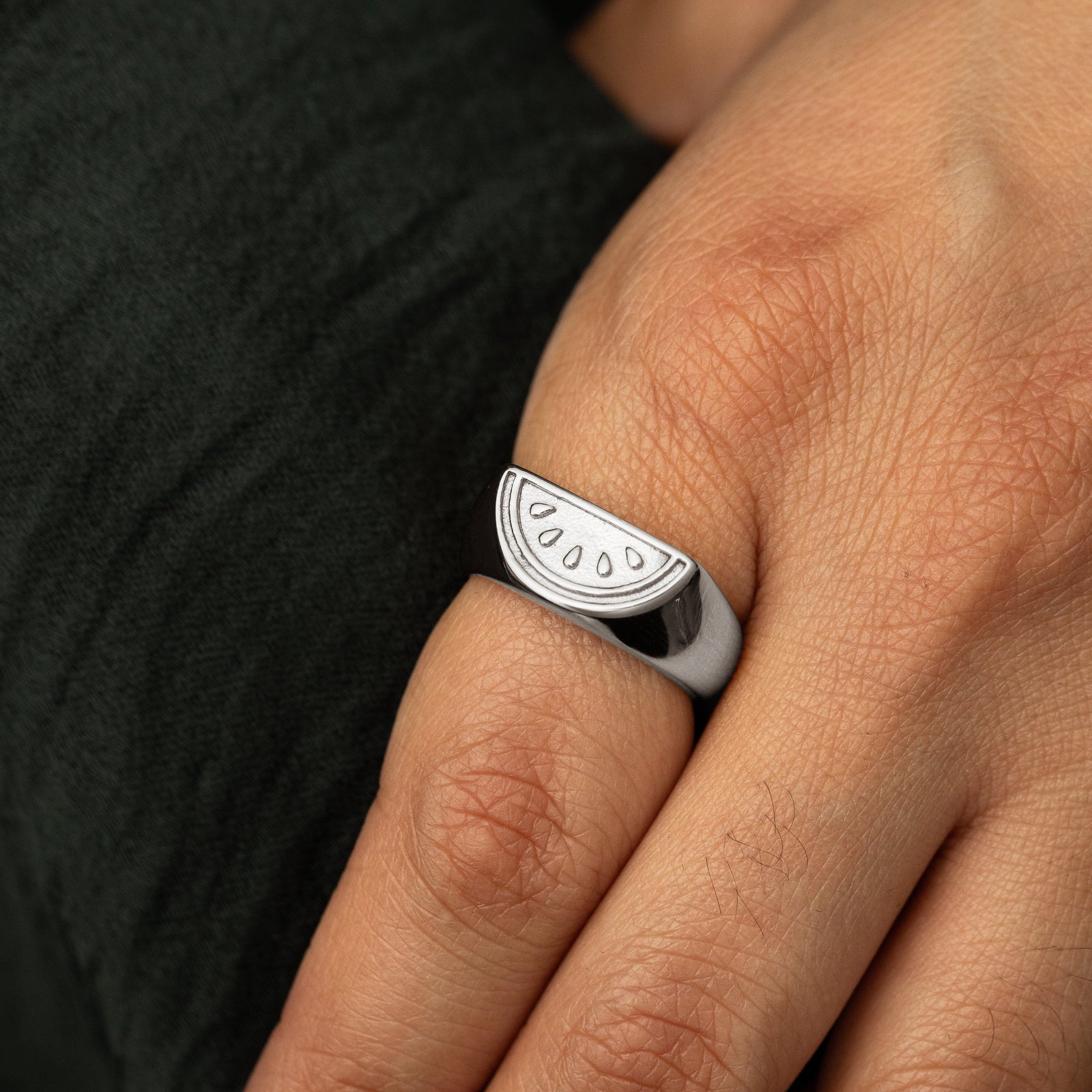 Close up of the silver Palestinian Watermelon Ring worn by the model on their index finger.