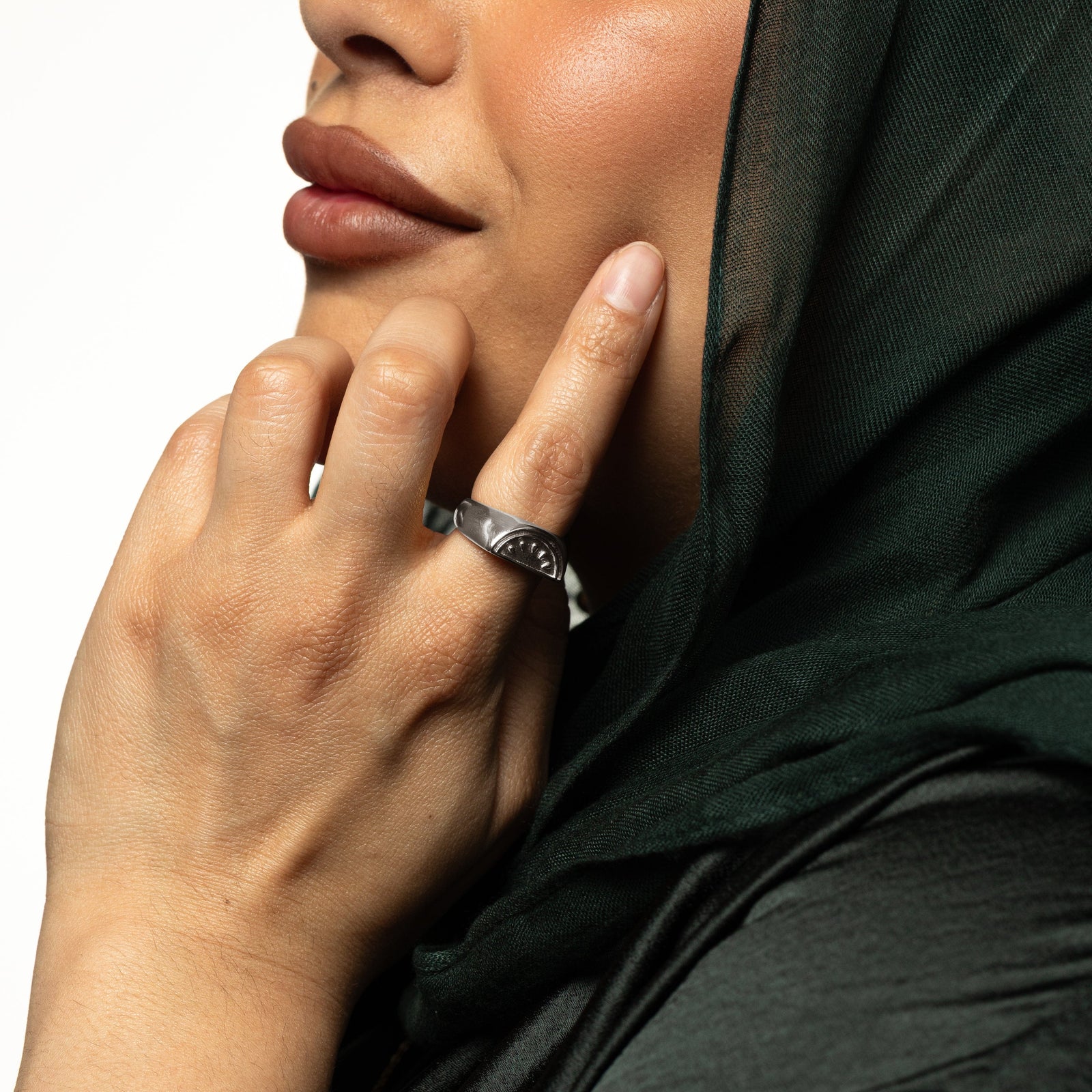 Model touching their face with their hand. The model is wearing the silver Palestinian Watermelon Ring on their index finger.
