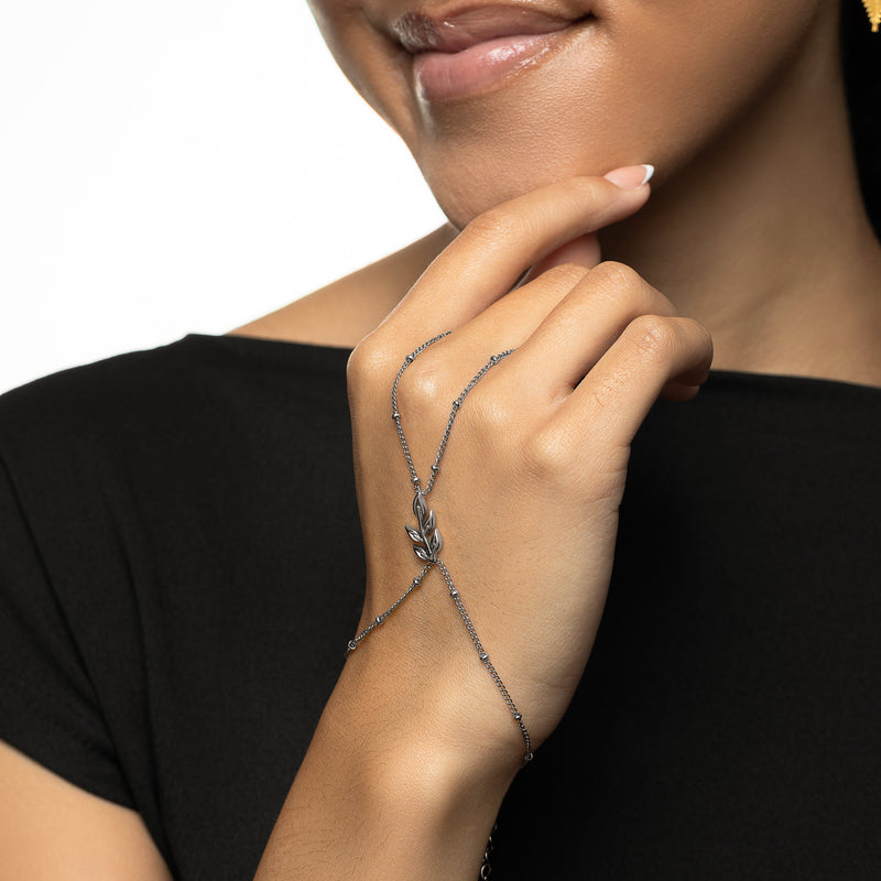 Model wearing the silver Palestinian Olive Branch Hand Chain pimage_ hand resting near the face.