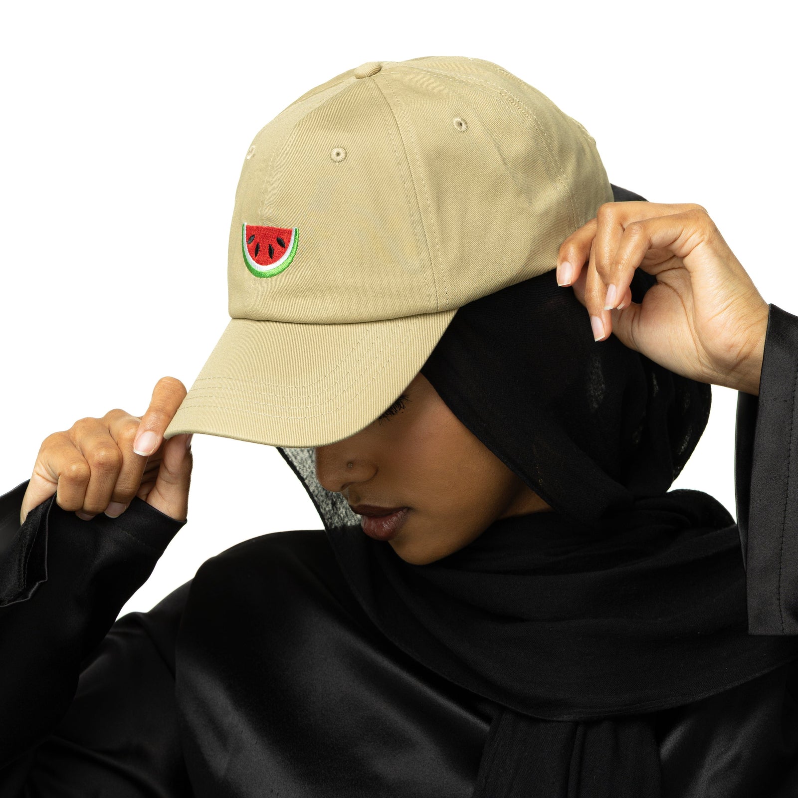 Side profile photo of the model wearing the beige Palestinian Watermelon Cap. The model is holding the tip of the cap.