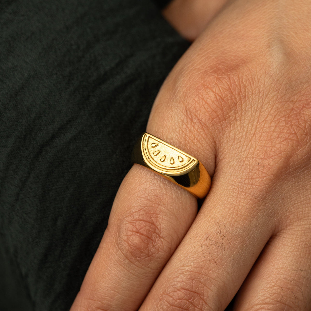 Close up of the gold Palestinian Watermelon Ring worn by the model on their index finger.