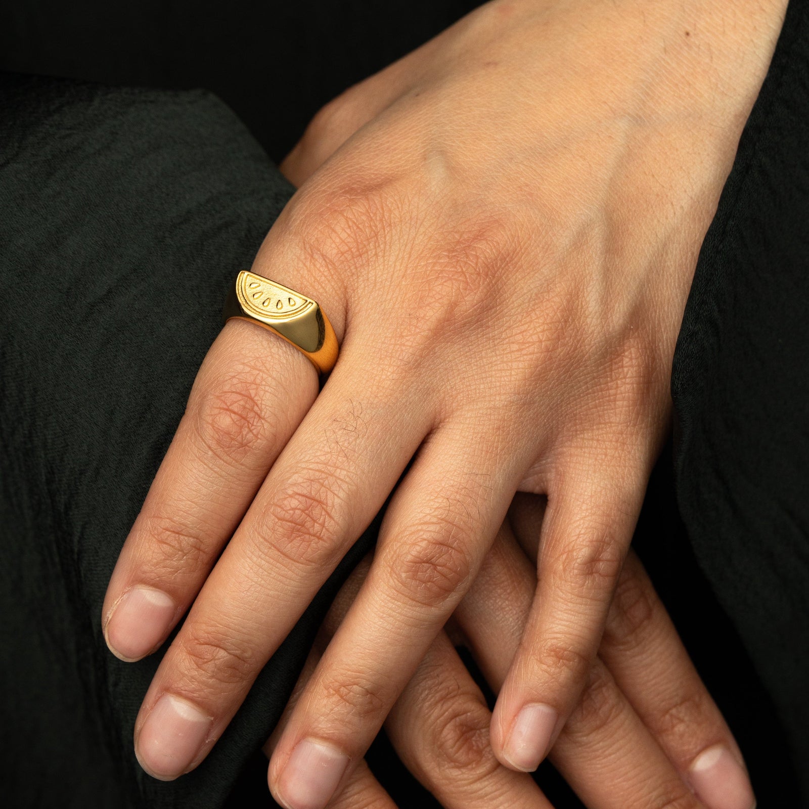 Photo of model's hand over the other. The model is wearing the gold Palestinian Watermelon Ring on their left index finger. 