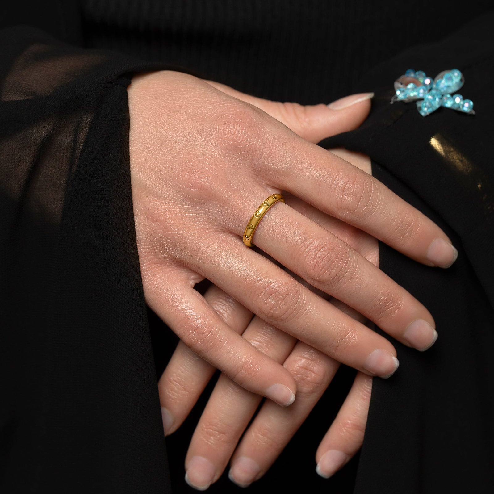 Photo of the model's hands. The model is wearing the gold Palestinian Watermelon Seed Ring on their right middle finger.