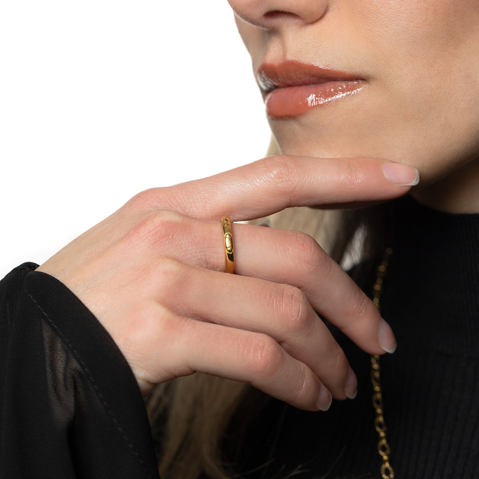 Model is touching their chin. The model is wearing the gold Palestinian Watermelon Seed Ring on their right middle finger.