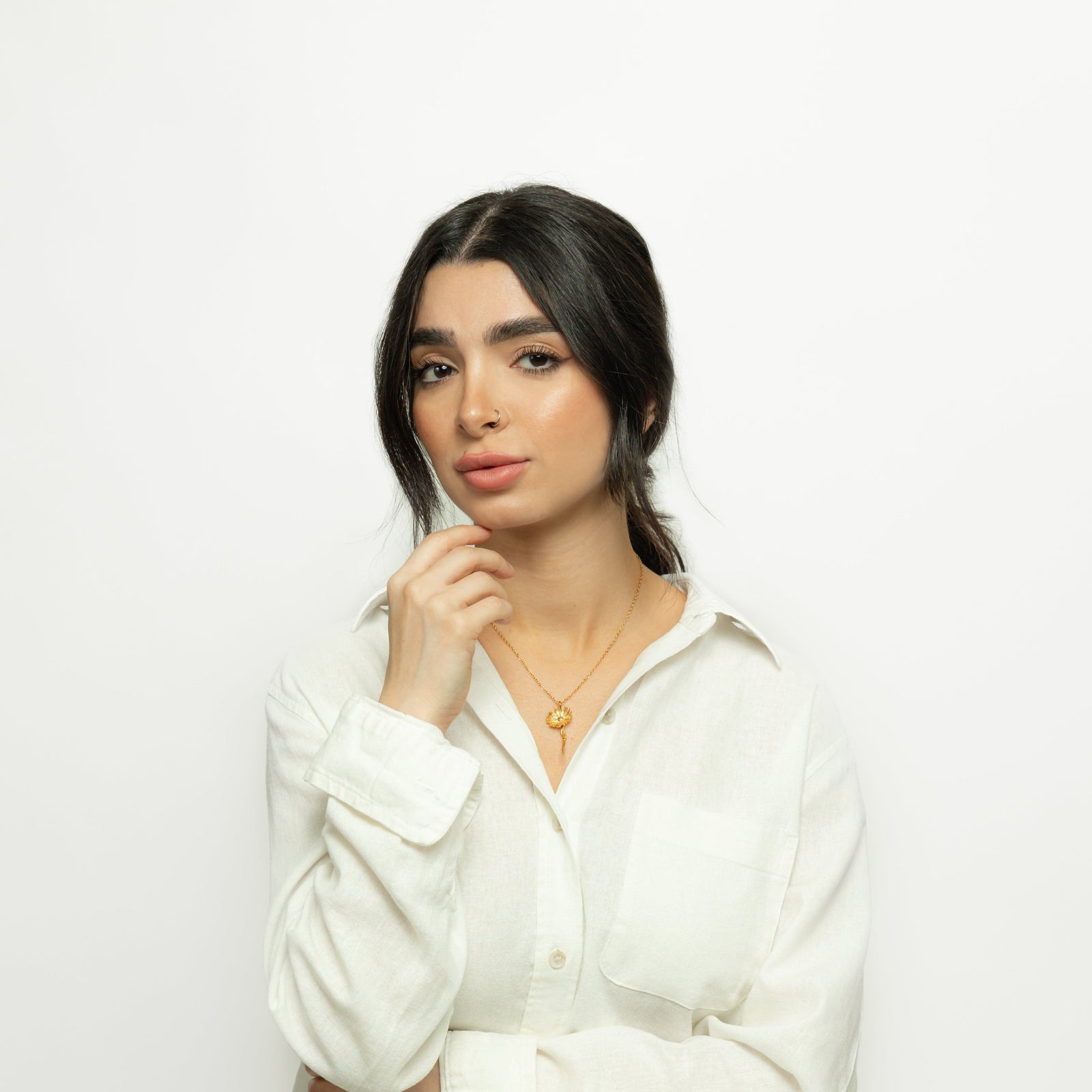 Photo of the model looking and posing for the camera. The model is wearing the gold Patience' Aster Necklace.