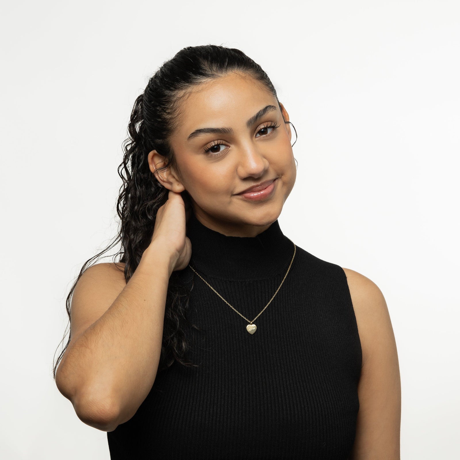 Photo of the model smiling to the camera. The model is wearing the gold Patience | صبر Charm Necklace