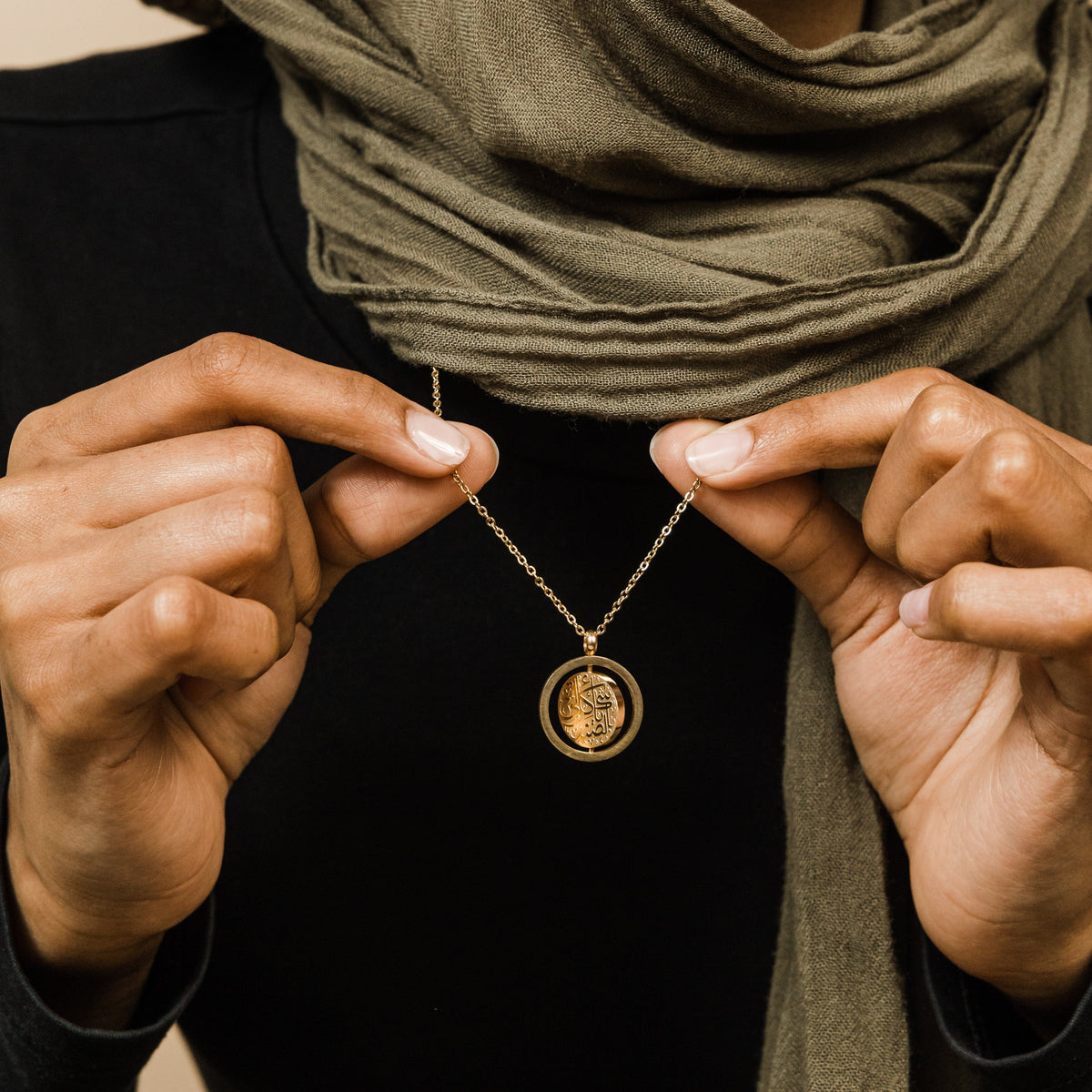 Close up of the gold Everything Comes with Patience Necklace as the model holds its chain to show the pendant.