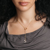 On-model view of the Pavé Olive Branch Lariat Necklace by Nominal, featuring a delicate 18k gold-plated chain and sparkling pavé olive leaf charms cascading from a central circular connector.