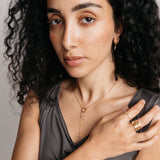 Model styled in 18k gold-plated Nominal jewelry featuring the Pavé Olive Branch Lariat Necklace paired with the Ayatul Kursi Ring Stack and Bezel Garden Ring.