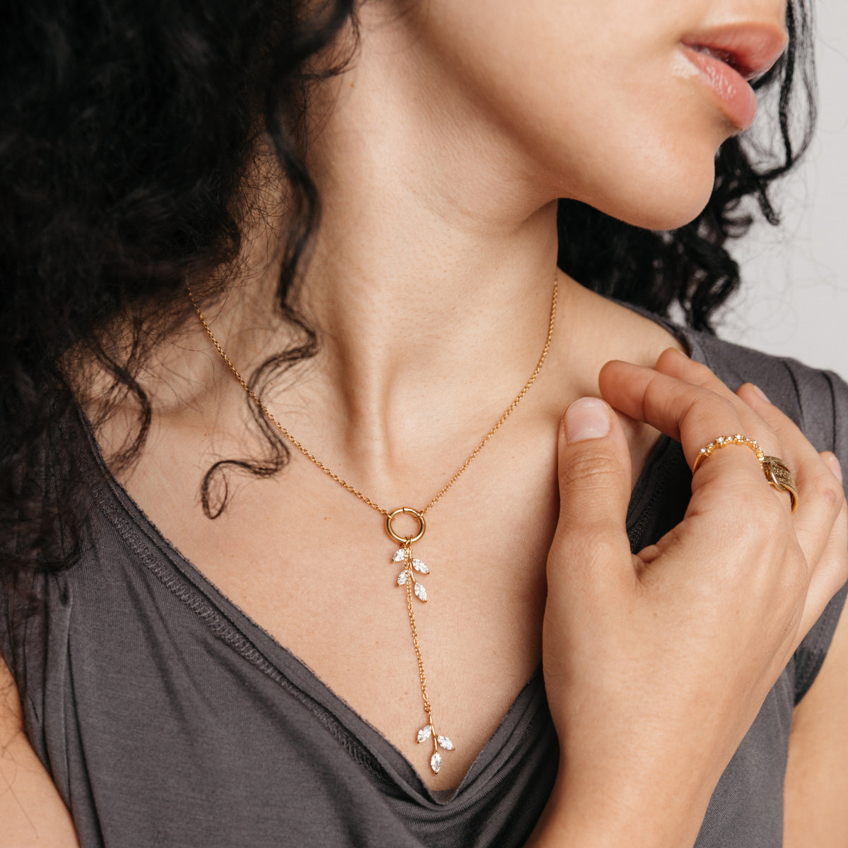 Model styled in 18k gold-plated Nominal jewelry featuring the Pavé Olive Branch Lariat Necklace paired with the Ayatul Kursi Ring Stack and Bezel Garden Ring.