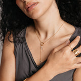 Model styled in 18k gold-plated Nominal jewelry featuring the Pavé Olive Branch Lariat Necklace paired with the Ayatul Kursi Ring Stack and Bezel Garden Ring.
