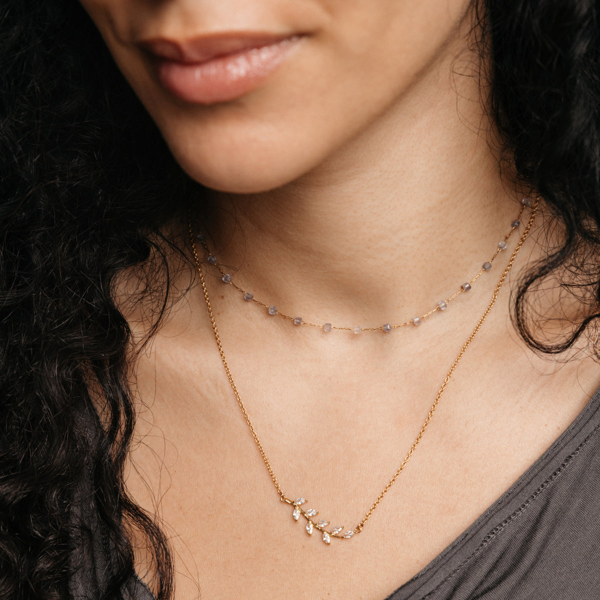 Layered necklace look featuring Nominal's Essential Iolite Micro Chain paired with the Pavé Olive Branch Necklace on a model.