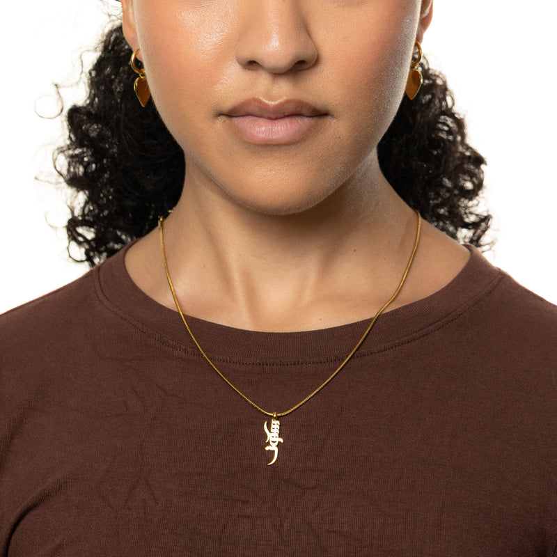 Woman wearing a gold peace of mind necklace 