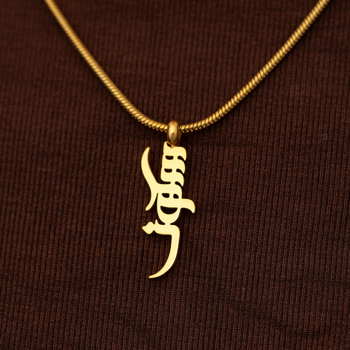 Gold Peace of Mind necklace on a brown textured background