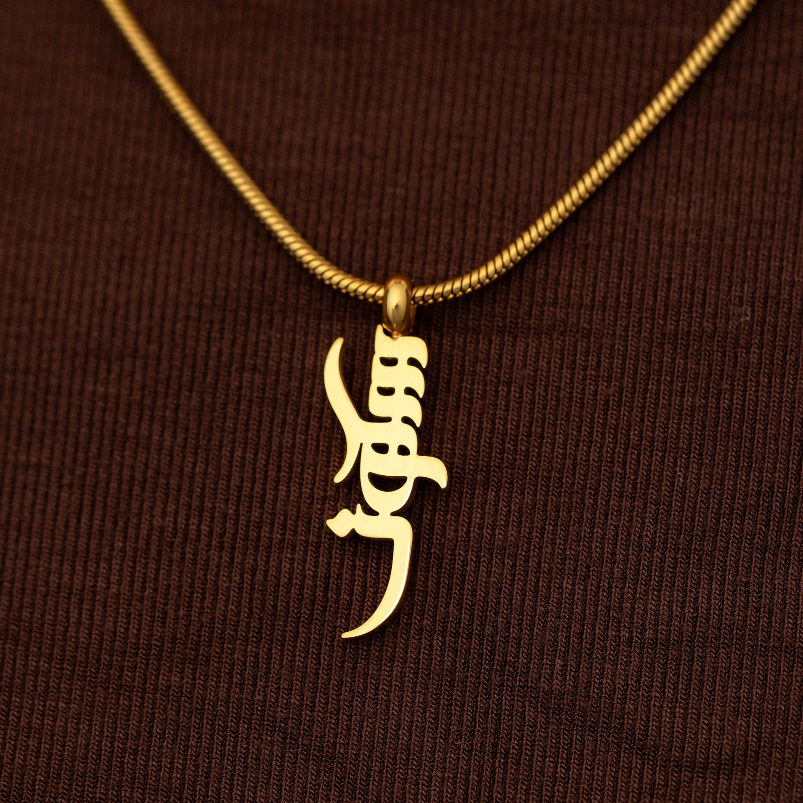 Gold Peace of Mind necklace on a brown textured background