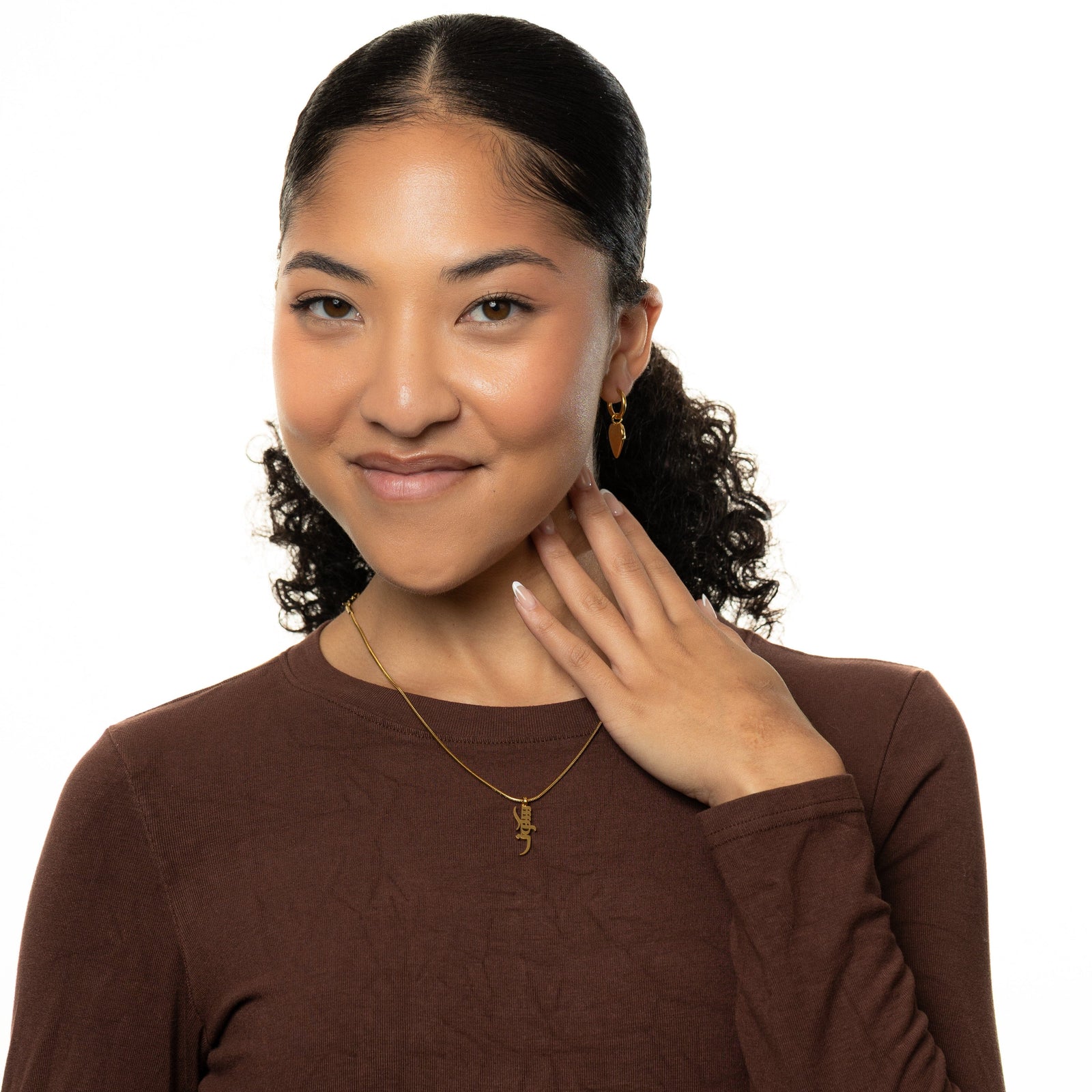 Woman wearing a brown tops and a gold Peace of Mind necklace