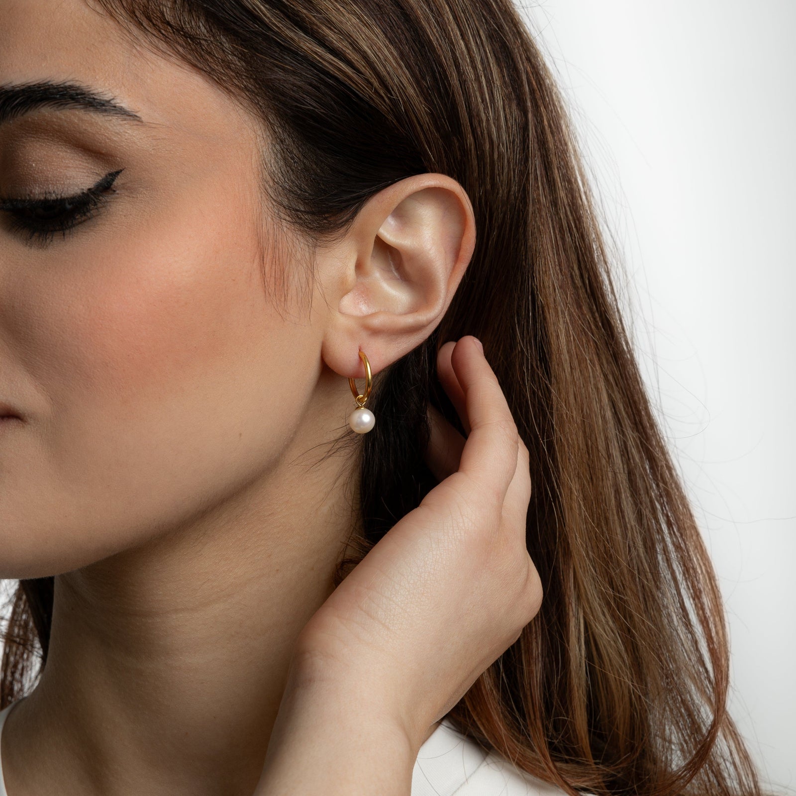 Close up of Pearl Hoop Earrings as worn by the model on their left ear.