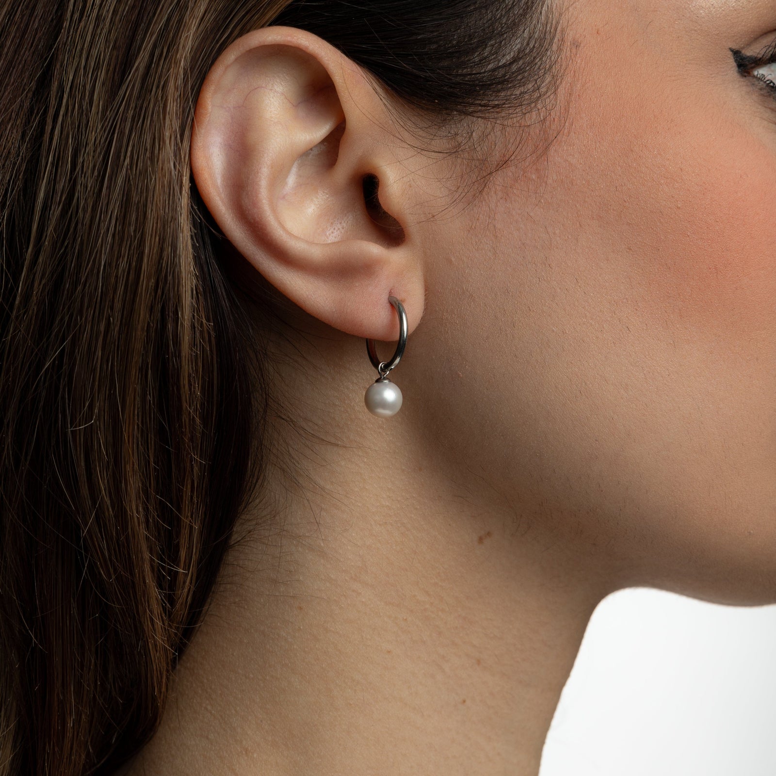 Close up of the silver Pearl Hoop Earrings as worn by the model on their right ear.