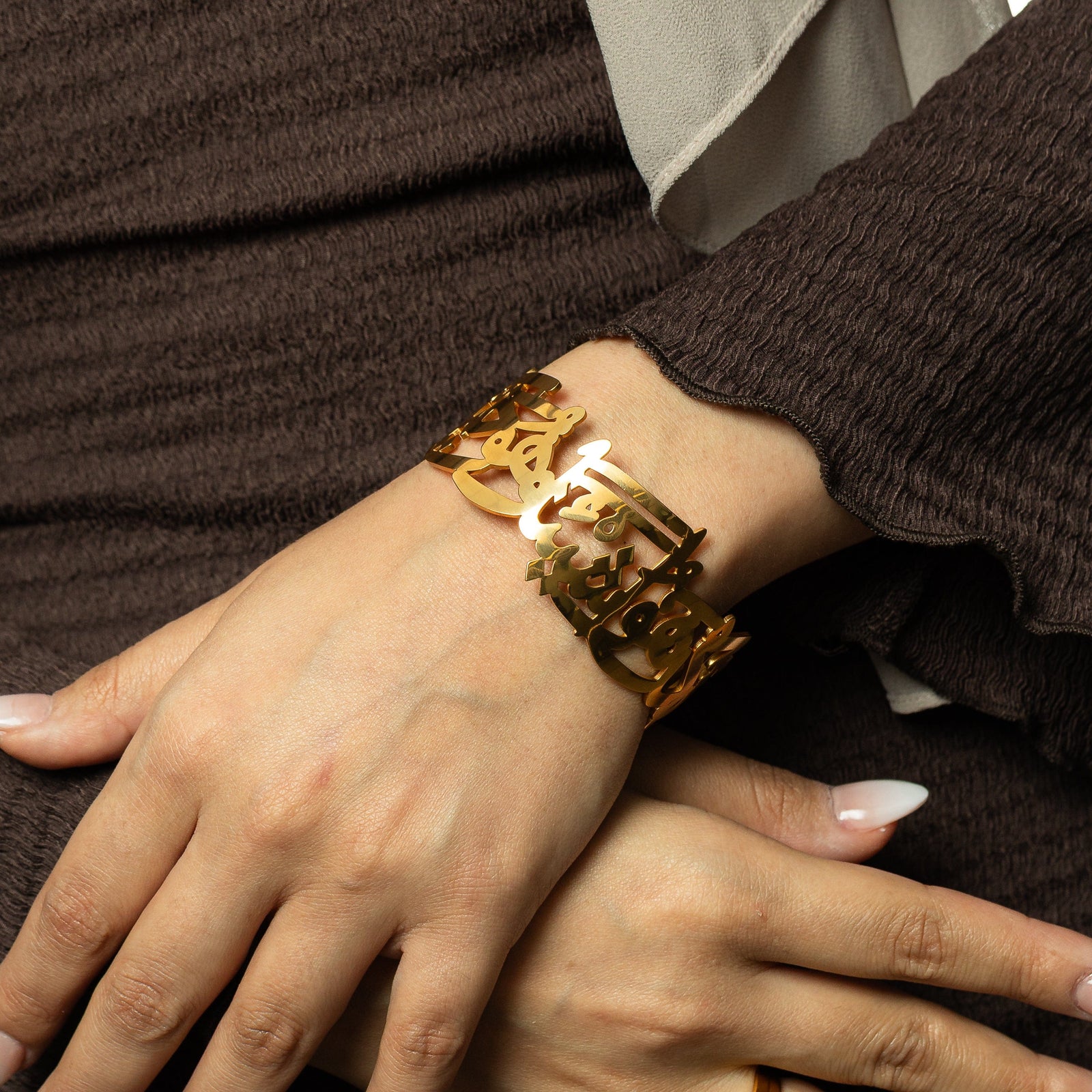 Woman wearing the gold ‘Perhaps you dislike something which is good for you’ Calligraphy Cuff, showing the open Arabic script design on the wrist.