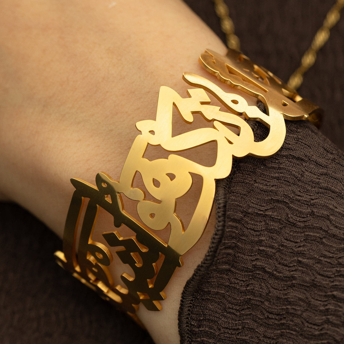 gold ‘Perhaps you dislike something which is good for you’ Calligraphy Cuff, showing the open Arabic script design on the wrist.