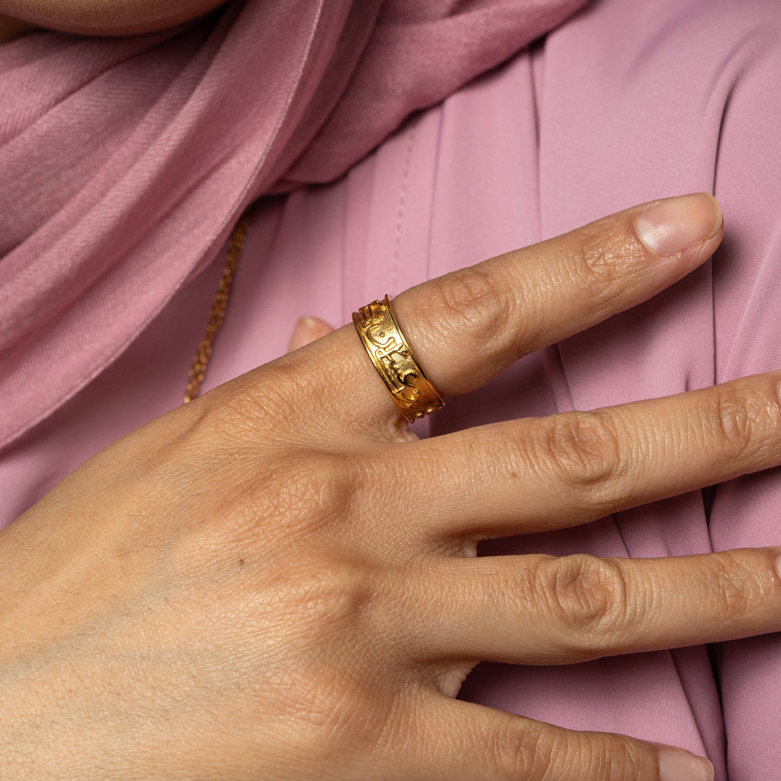 Photo of the model's right hand. The model is wearing the gold "Perhaps you dislike what is good for you" Ring on their right index finger