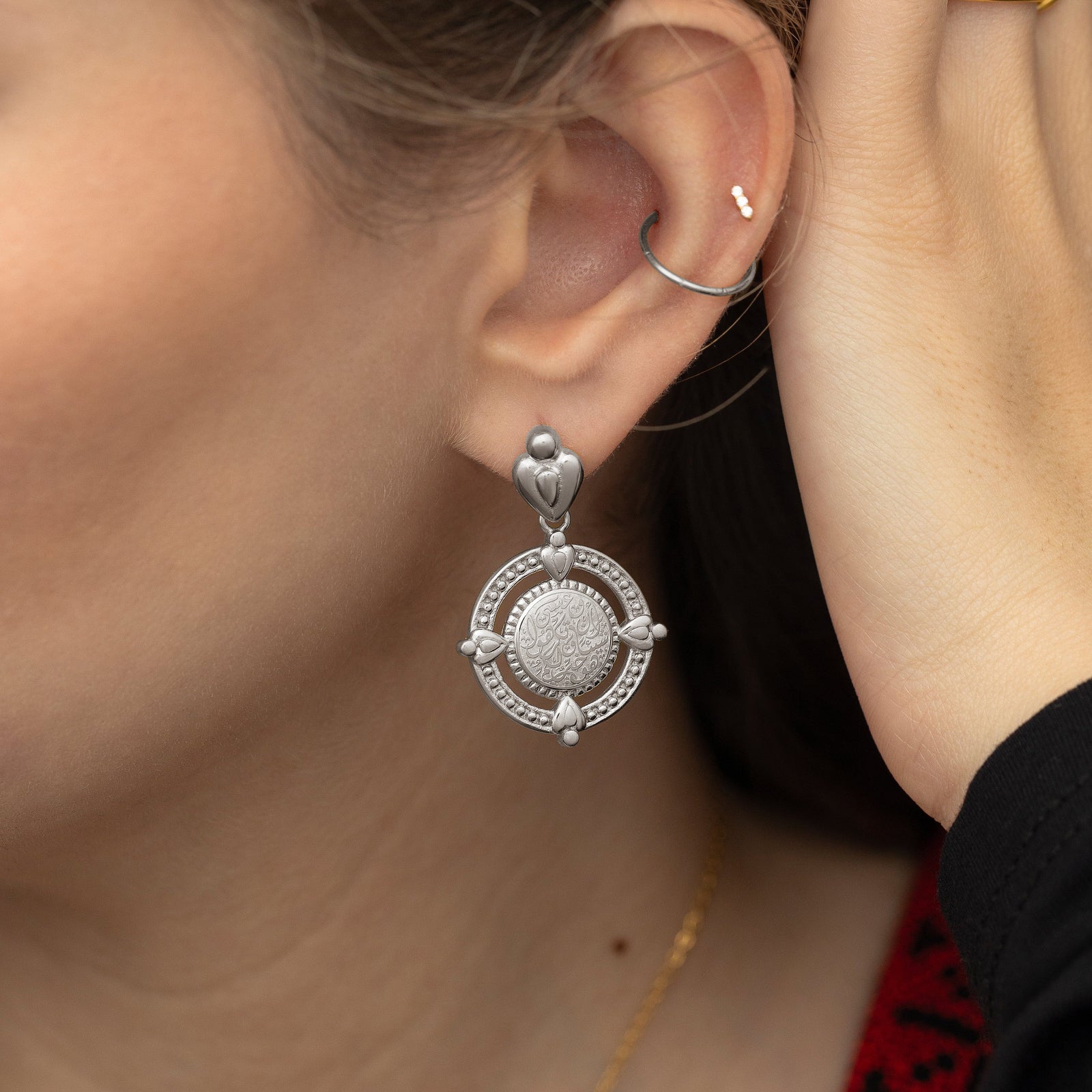 Close up of the silver earring worn by the model.
