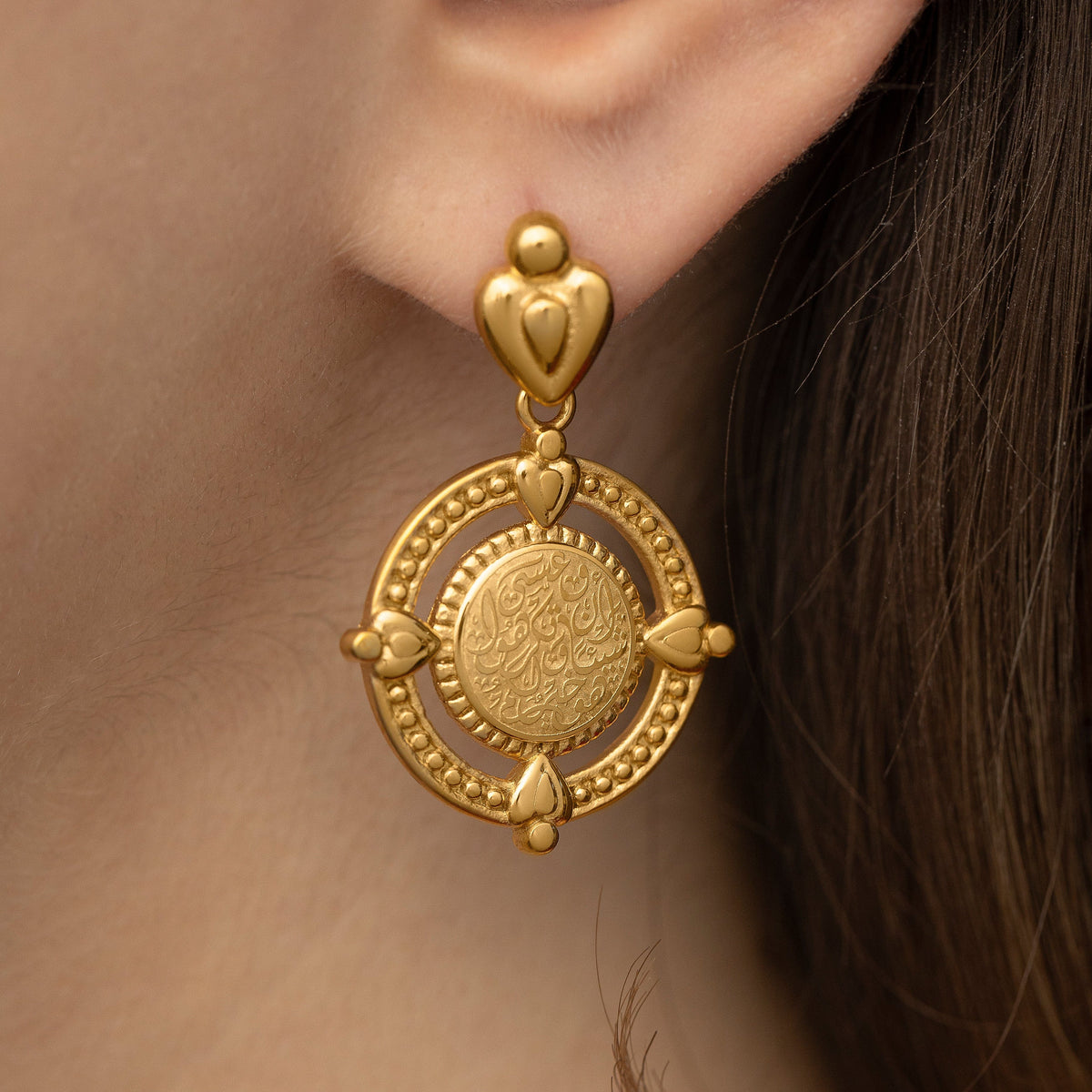 Close up of the gold earring worn by the model.